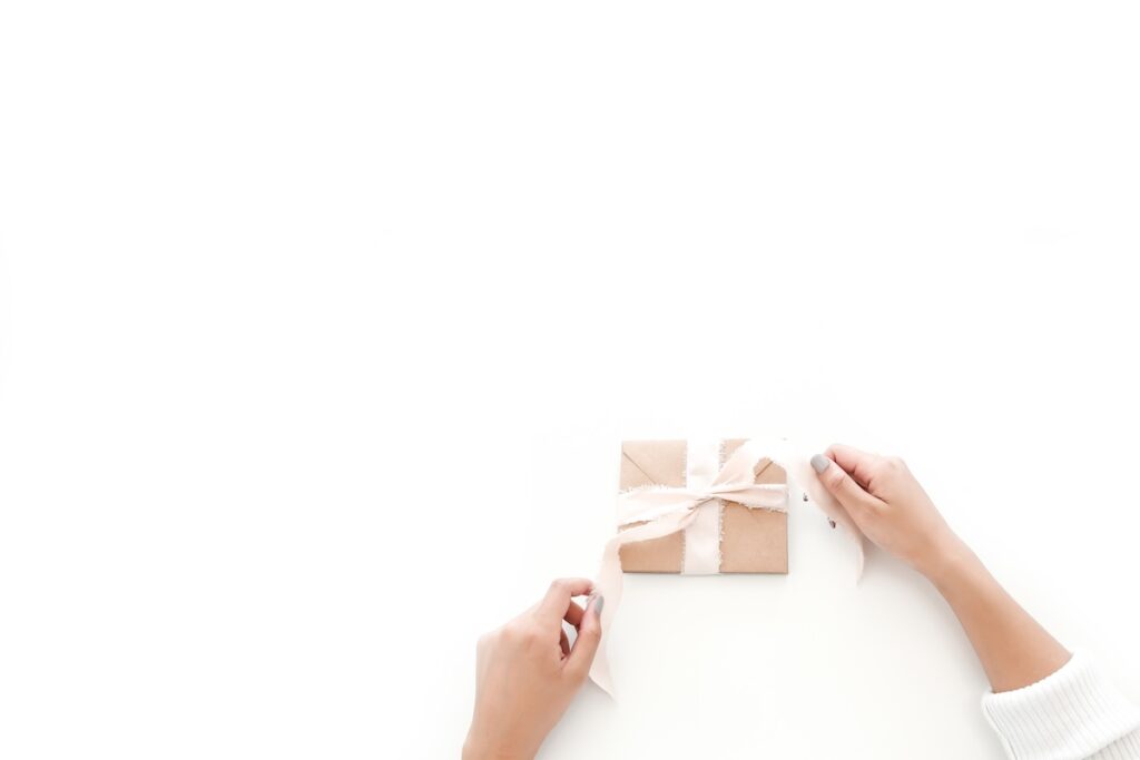 Hands tying a ribbon around a wrapped gift box